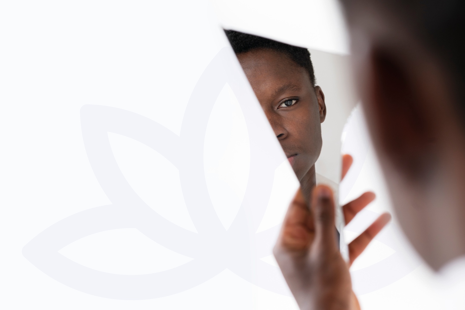 A young man looking into his reflection in a broken shard of glass.