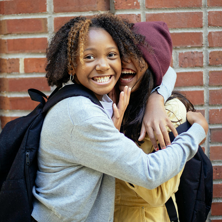 Two teenagers smiling and laughing while hugging eachother