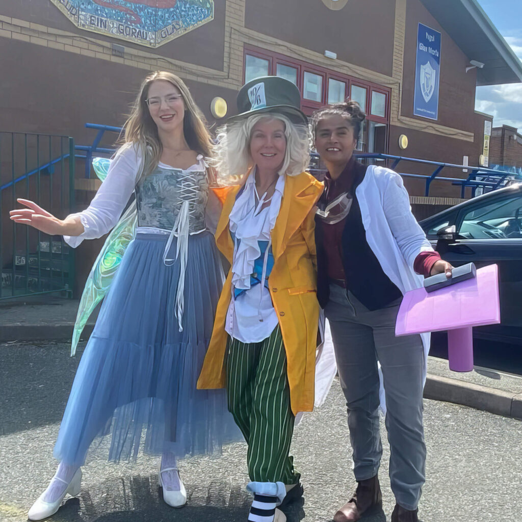 Shilpa and Geraldine in fancy dress smiling while stood outside a primary school