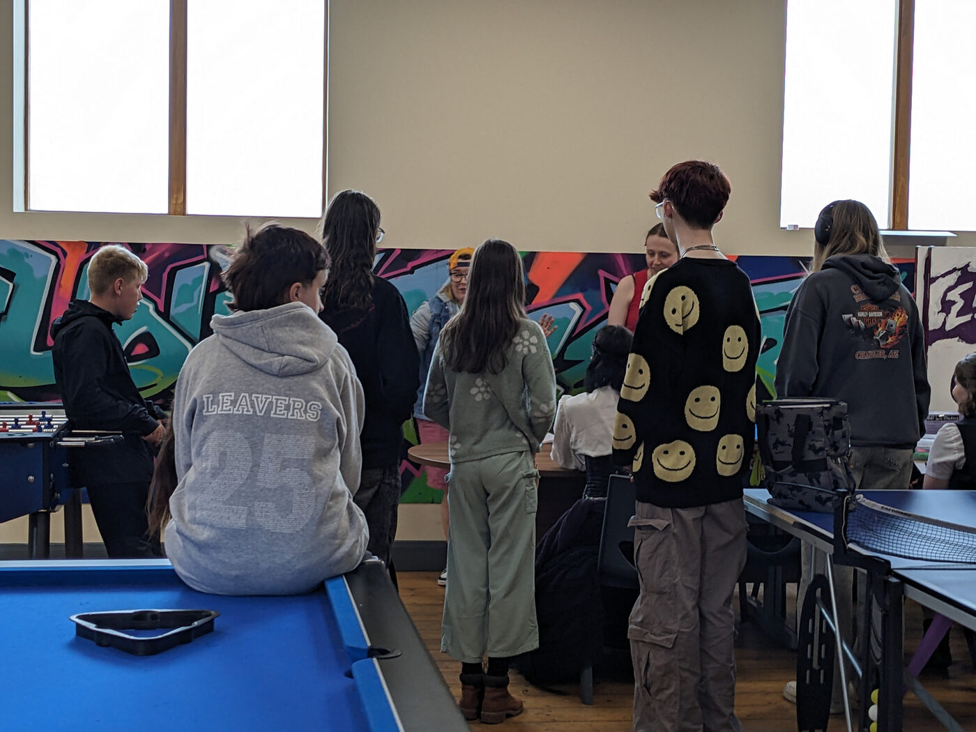 Young people gathered around a pool table during a Friday Mix session